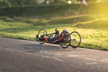 Cyclist on the handbike in maximum effort at a special bicycle road under the evening sunset in summer - 205733315