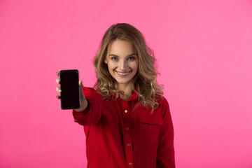 young joyful beautiful girl in red attire on a pink background with phone in hand