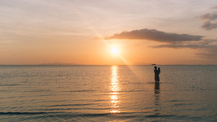 Fototapeta premium Silhouette Dad and son are walking together on the beach and sea with the sunset background and copy space.