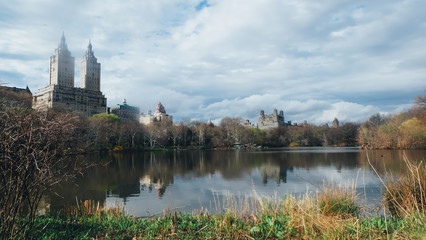 Fototapeta na wymiar The San Remo View from Central Park at Manhattan, New York with lake, cloud sky, grass, and reflection.