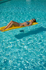 Woman relaxing on donut lilo in the pool at private villa. Inflatable mattress. Summer holiday idyllic.