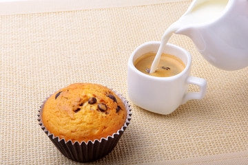 Perfect morning breakfast with Delicious homemade cupcakes with raisins, chocolate chips, espresso coffee in white cup and milk on textile background. Muffins.