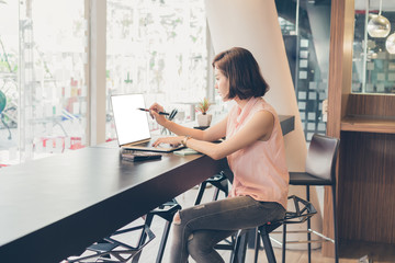 Young beautiful asian woman working about financial with white screen laptop for graphic montage.financial and accounting concept.