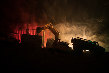 Construction site on a city street. A yellow digger excavator parked during the night on a construction site. Industrial concept table decoration on dark foggy toned background