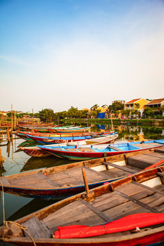 HOI AN, QUANG NAM, VIETNAM, April 26th, 2018: Boats by the river in ancient town Hoi An with view of typical yellow houses
