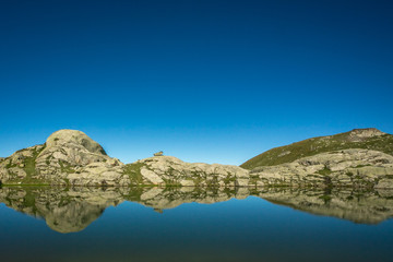 A beautiful mountain panorama on Italian. Peace, serenity, solitude and silence on a beautiful spring day with the blue sky reflected in the water of the pond.