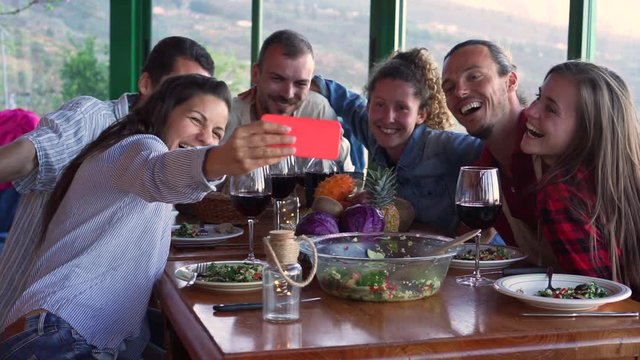 Slow motion of happy friends taking selfie during vegetarian dinner at home - Group of yung people having fun with trends technologies - Youth lifestyle, tech and friendship concept
