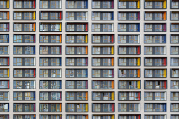 Fototapeta na wymiar Facade of modern building of concrete and glass with colored inserts on the windows as texture, background, abstract