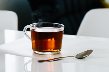 A cup of black tea stands on a white table