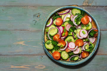 Vegetarian salad of fresh vegetables on a green wooden background. Top view, copy space.