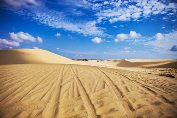 Sand dunes near Mui Ne. Group of off roads on top of dunes in the background. Sunny day with blue sky and clouds