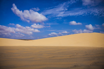 Plakat Sand dunes near Mui Ne. Group of off roads on top of dunes in the background. Sunny day with blue sky and clouds