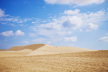 Sand dunes near Mui Ne. Group of off roads on top of dunes in the background. Sunny day with blue sky and clouds