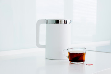 A teapot and a cup of tea stand on the table