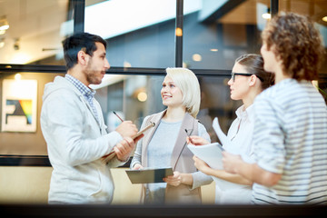 Group of young specialists planning new working day and discussing their plans in office