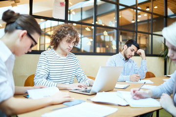 Several young co-workers making their working plans or preparing reports for briefing in office