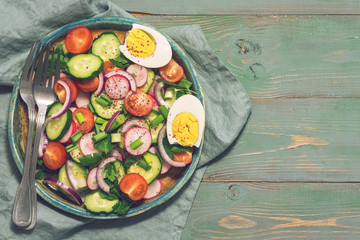 Vegetarian salad of fresh vegetables on a rustic green background. Top view, space for text.