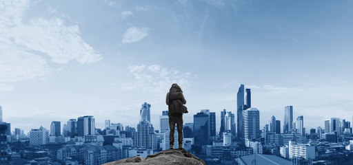 Fototapeta na wymiar a man with backpack standing on the rock looking at the city. Business success concept