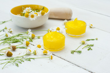 medical cream and daisy herbal flowers on white wood table background