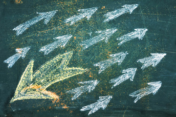 chalk drawn arrows on the blackboard, one of which is in opposite direction from all others. individuality and think different stand out of crowd concept.