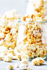 Caramel sweet popcorn in glass jars, gray background, selective focus