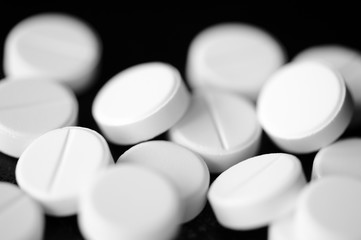 White pharmaceutical pills on a black background close up