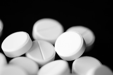 White pharmaceutical pills on a black background close up