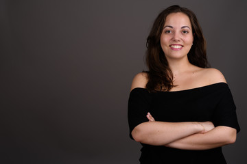 Young beautiful woman wearing black off-shoulder top against gra
