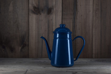 A blue metal kettle on a wooden floor.