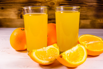 Oranges and glasses with orange juice on a wooden table