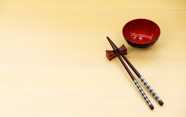 Top view of chopsticks red bowl on wood table background.Flat lay