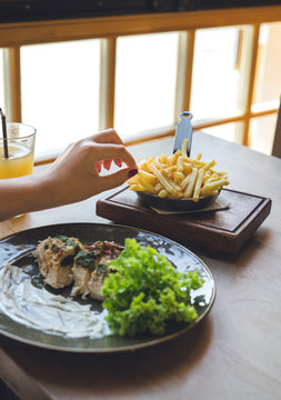 Girl hand holds french fries. Meat, salad and sauce