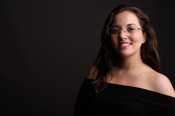 Young beautiful woman wearing black off-shoulder top against gra