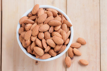 Almond nut in a ceramic bowl against wooden table