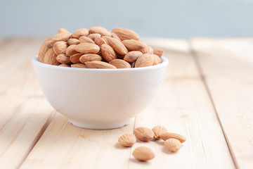 Almond nut in a ceramic bowl against wooden table