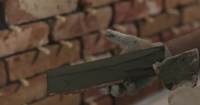 Slow motion closeup worker applying concrete glue to brick tile
