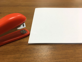 Red stapler with a white sheet of paper on the table, copy space, mockup. Office concept
