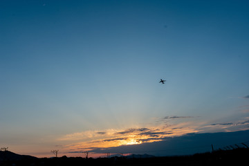Avión saliendo del aropuerto. el avión se ve pequeño y el atrdecer y montañas de fondo
