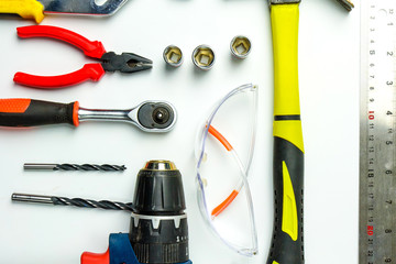 Obraz premium Set of construction tools on white background as wrench, hammer, pliers, socket wrench, spanner, tape measure, electric drill,safety glasses, screwdriver