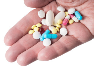 Pill, tablets and capsules in the palm of the hand on a white background