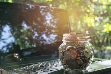 Coins in jar with laptop, Concept finance business and saving investment.