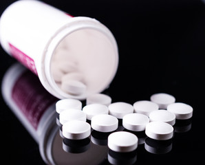 Pills from bottle on the black background.