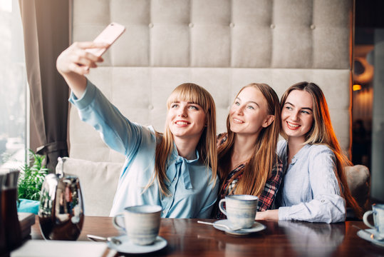 Three girlfriends makes selfie on camera in cafe