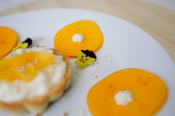 dessert tart with fruit, cream, plum, flowers, mint, almonds