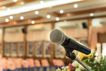 Microphones on abstract blurred of speech in seminar room or front speaking conference hall light, color chairs for people in event meeting convention hall in hotel. Vintage tone