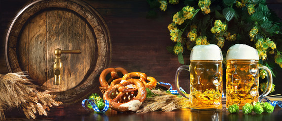 Oktoberfest beer barrel and beer glasses with soft pretzels, wheat and hop