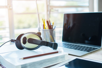 Student learning online study concept : Headphones on books and computer with pens box in working...