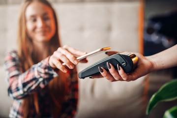 Young woman pay by mobile phone in cafe
