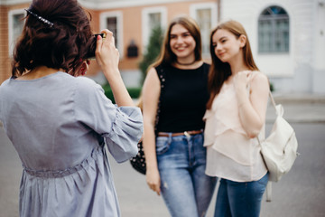Fototapeta premium Photography, hobby, leisure, travel, sightseeing, fashion. Young beginner photographer take picture of women models at city background