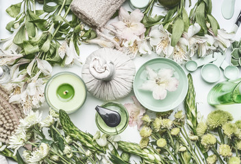 Green herbal spa setting with water bowl, flowers, candle, massage  balls, cosmetic products, herbs...